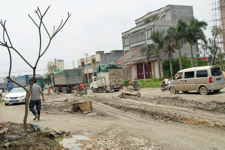 合浦县山口镇325国道某段成烂泥路长期得不到维修居民在道路上插秧