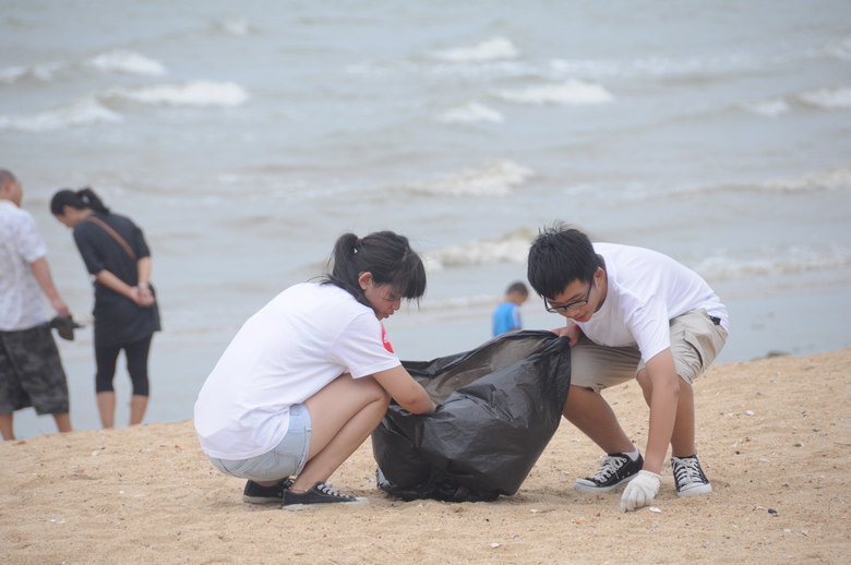台风天志愿者和90后女生北岸海滩捡垃圾并肩骑行还净海滩公益活动