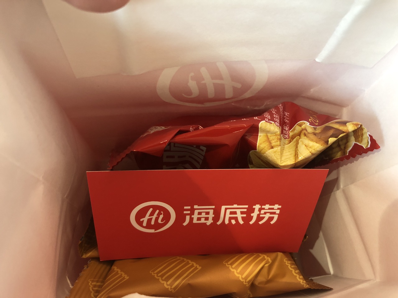 纸袋里面也是小零食,还有一张海底捞的名牌,有海底捞排队的二维码