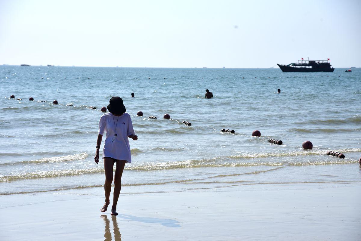 海边,一个小姐姐正穿着短袖和热裤在玩水,如果不是知道现在是11月,你